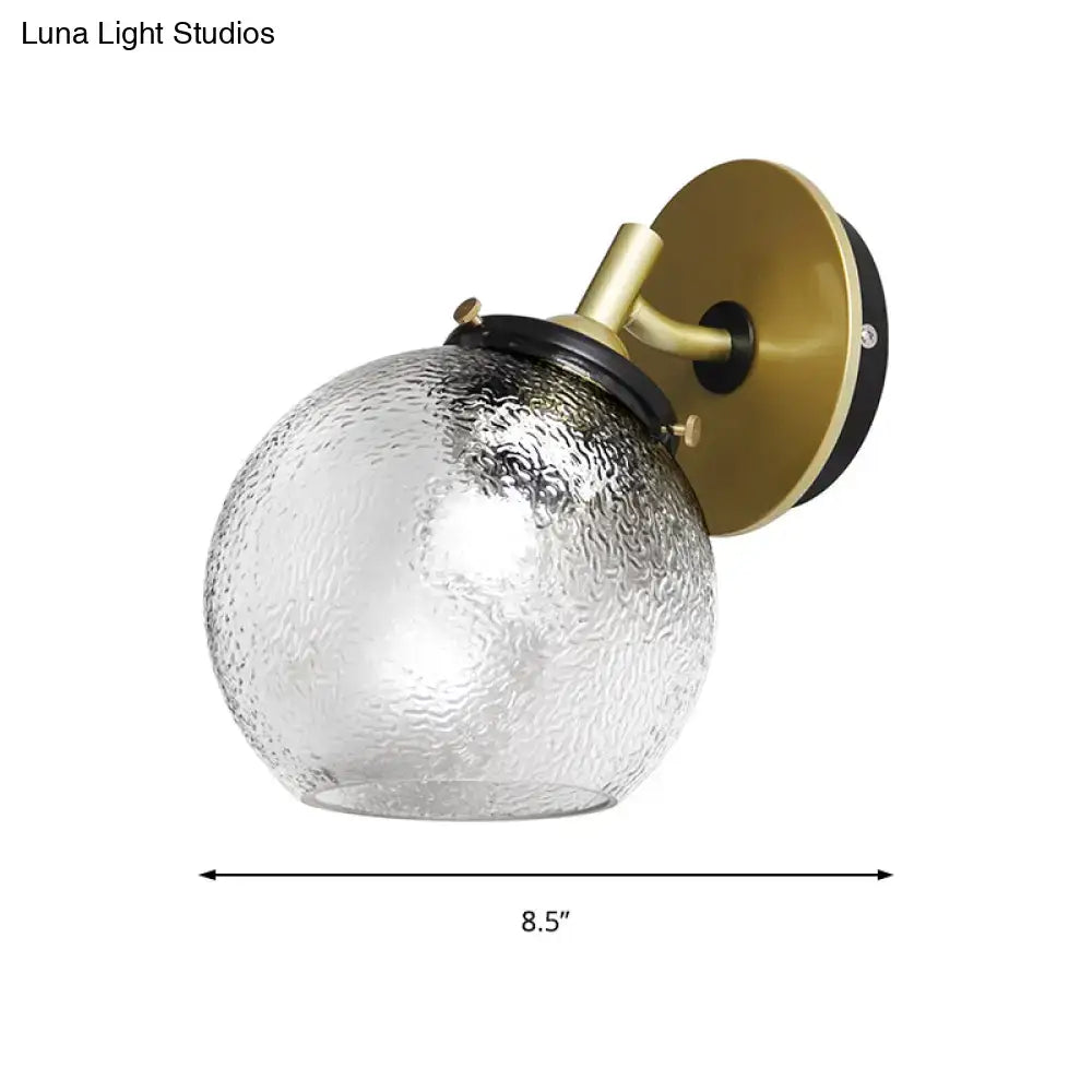 Minimalist gold water glass wall sconce with textured clear glass globe and brass fixture for living room
