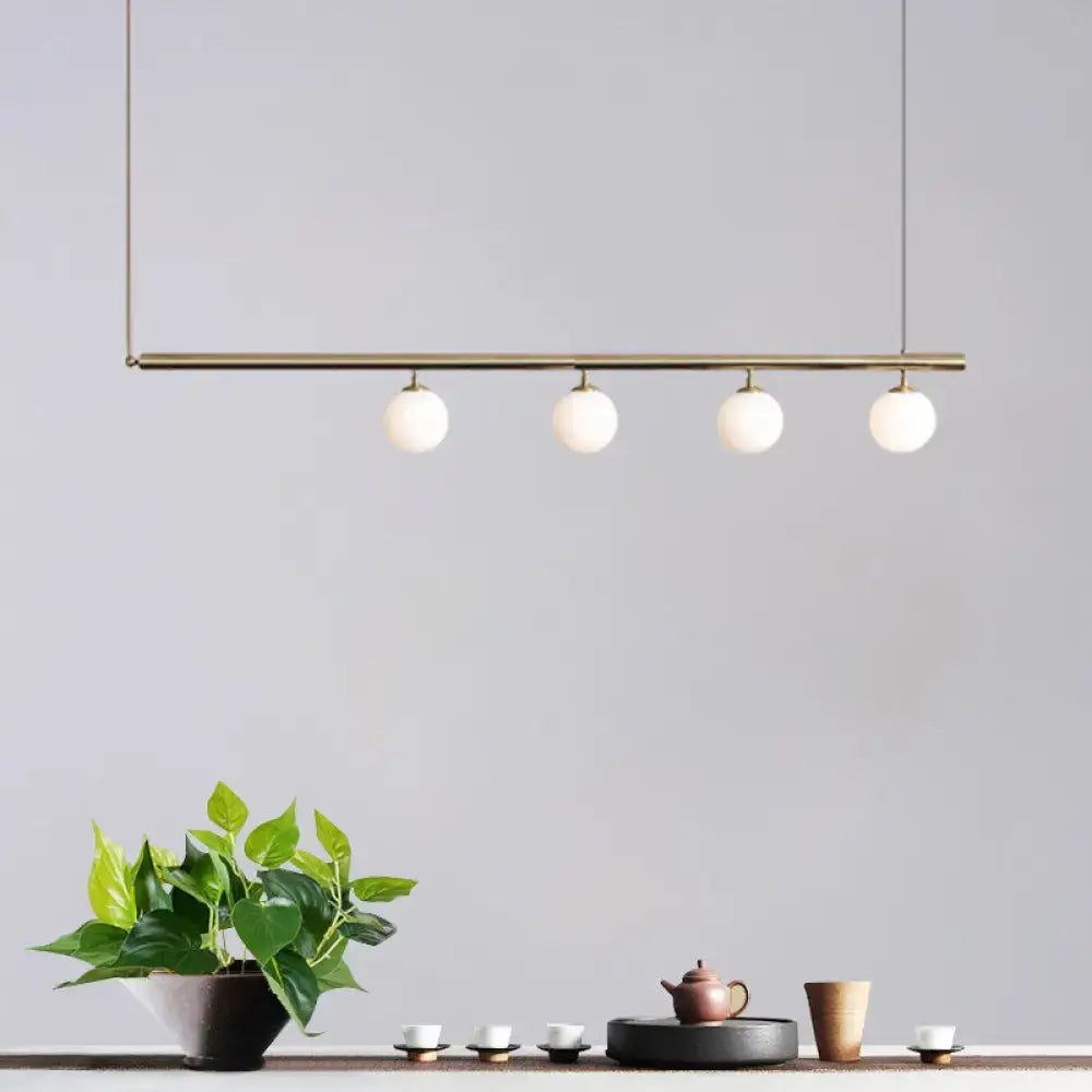 Modern brass pendant light with four white glass bulbs in a DecorBites dining room golden glass shade chandelier