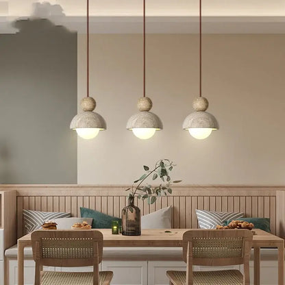 Three gray concrete pendant lights with matte finish and warm cords hang above a wooden dining table decorbites glass ball