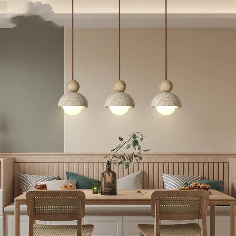 Three gray concrete pendant lights with matte finish and warm cords hang above a wooden dining table decorbites glass ball