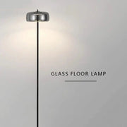 Minimalist gray glass floor lamp with a sleek chrome cylindrical shade and black metal stand for living room use
