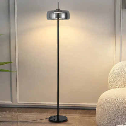 Minimalist gray glass floor lamp with a sleek black metal pole and reflective chrome dome shade for living room