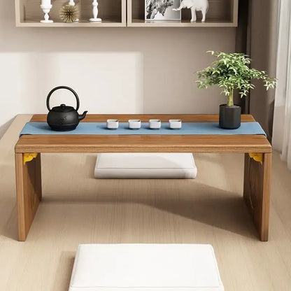 Minimalist light brown bamboo folding table with blue runner set for tea with black teapot and white porcelain cups