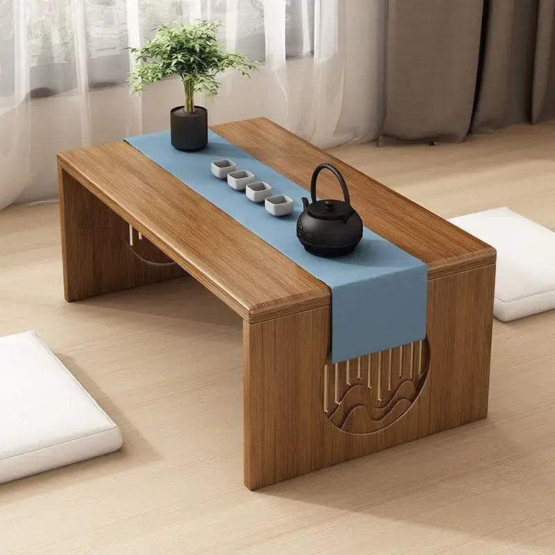 Minimalist light brown bamboo folding table with carved wave design and blue runner holding teapot and cups