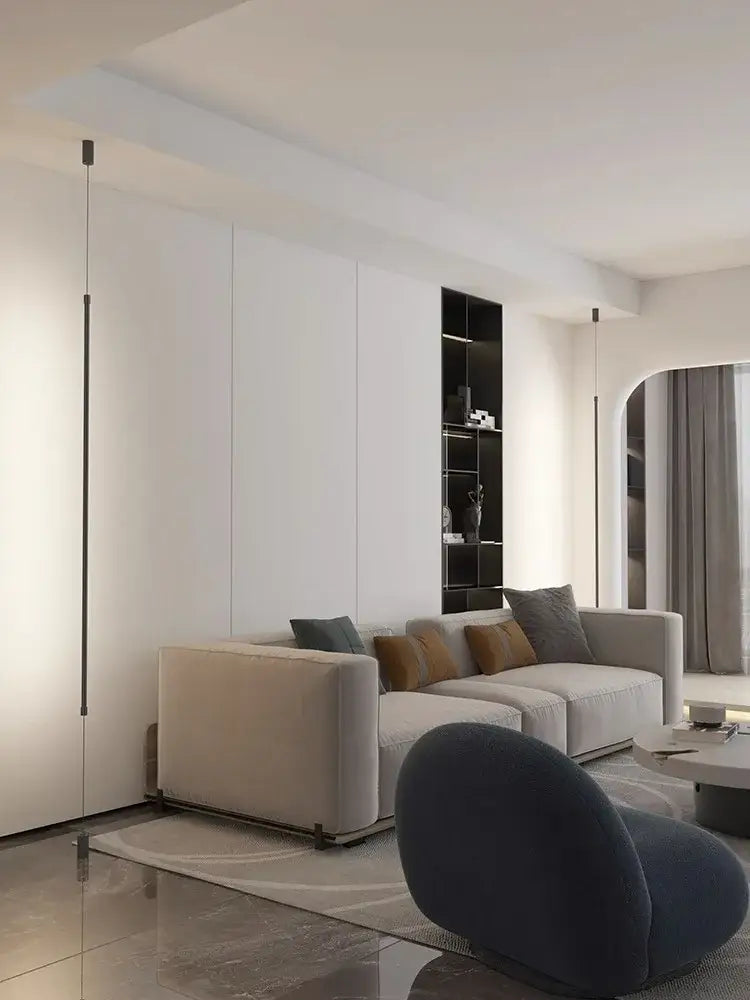 Modern beige sectional sofa with plush cushions and sleek metal legs beside minimalist matte black straight strip bedside pendant light