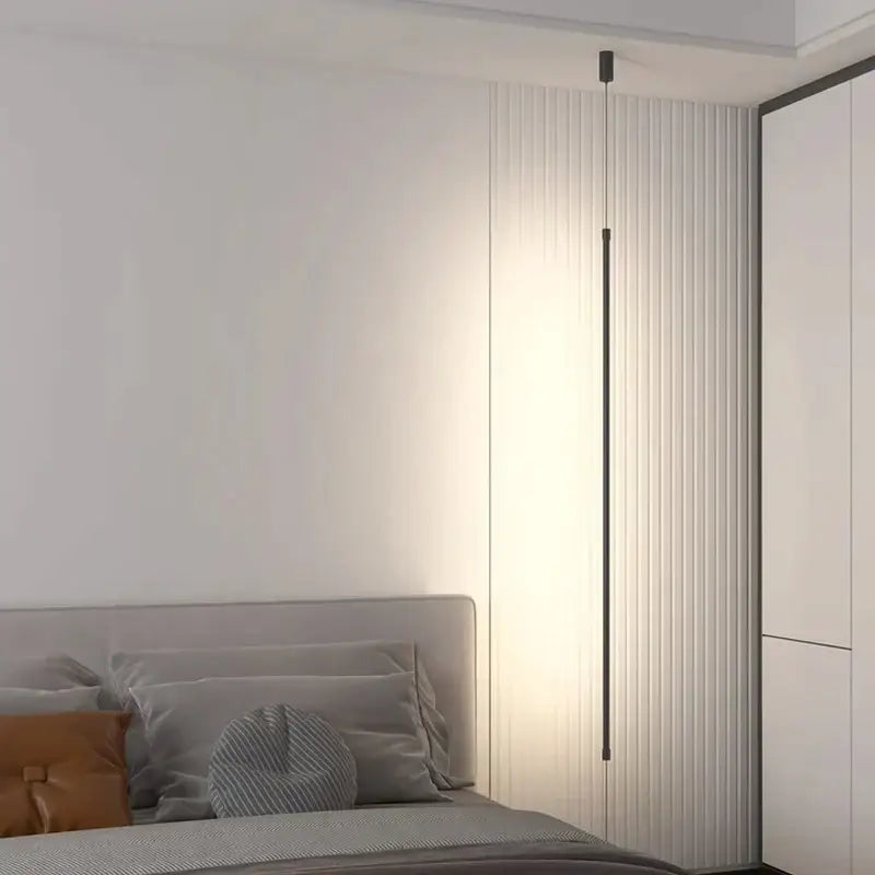A minimalist matte black bedside pendant light with a straight strip design and warm white light through vertical slats