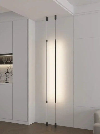 Minimalist matte black cylindrical pendant light strip with two slender rods emitting warm glow for bedroom use