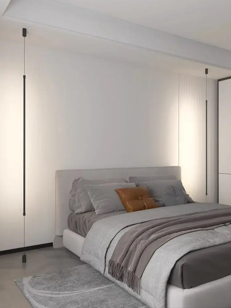 Modern gray upholstered bed with tufted headboard and layered bedding illuminated by minimalist matte black pendant light strip