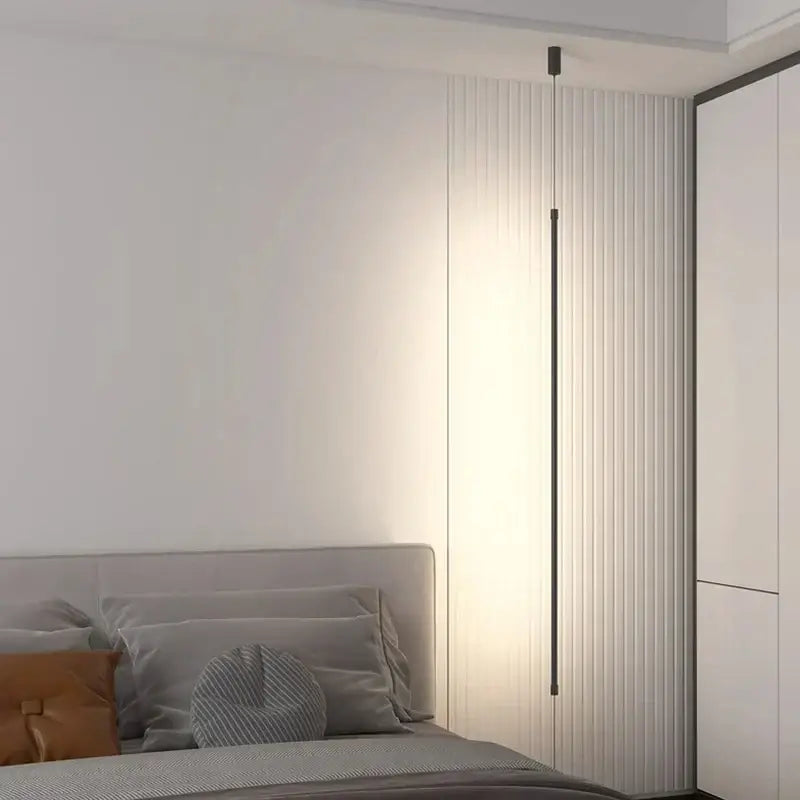 A minimalist matte black cylindrical pendant light strip with warm ambient light for bedroom lighting