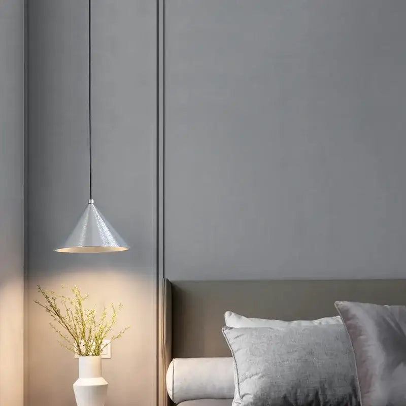 A sleek metallic matte black pendant light chandelier with a cone shape hangs from a thin black cord for dining room