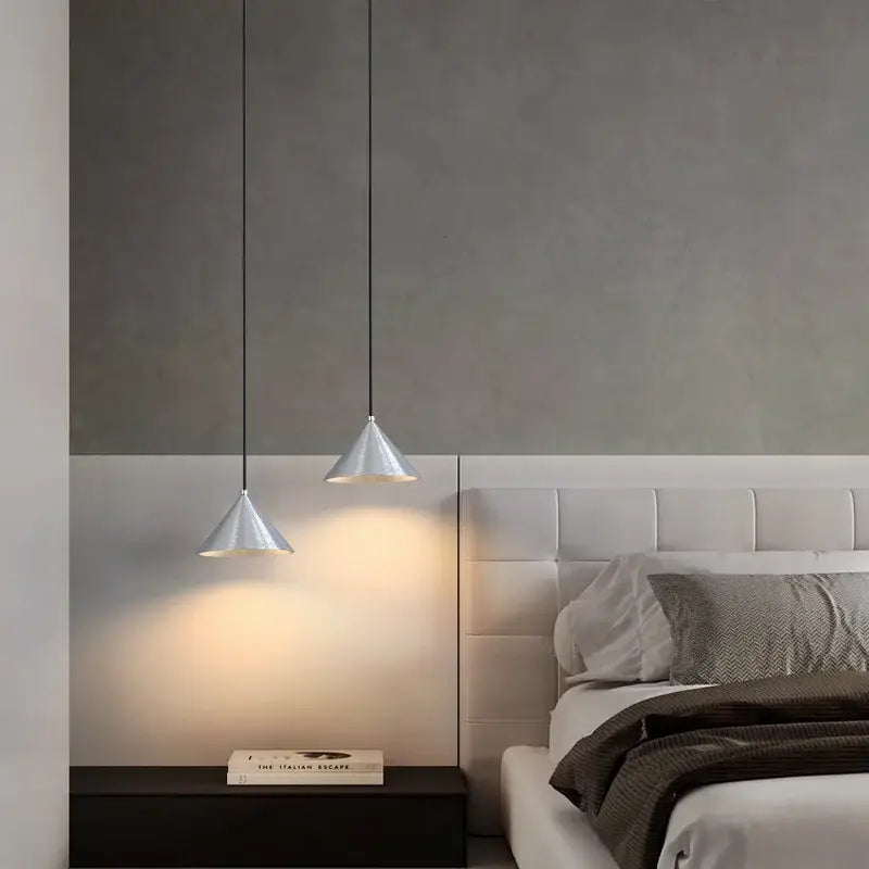Two sleek silver cone-shaped pendant lights hang from black cords as part of a minimalist matte black pendant light chandelier
