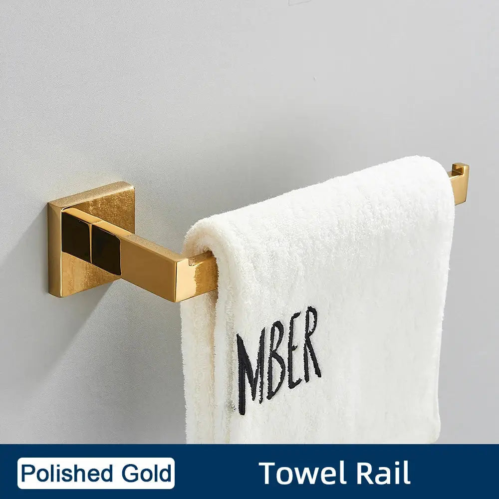 Polished gold towel rail with sleek modern design holding white embroidered towel in minimalist stainless steel bathroom accessories set