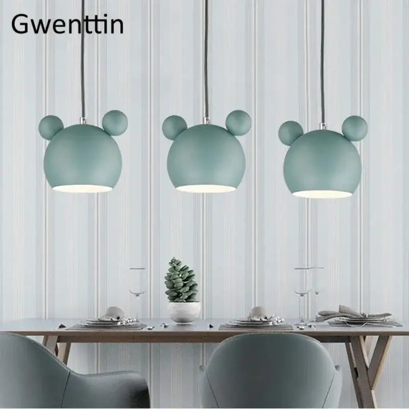 Three mint green minimalist matte cartoon mouse pendant lights hang above a dining table decorbites pendant light