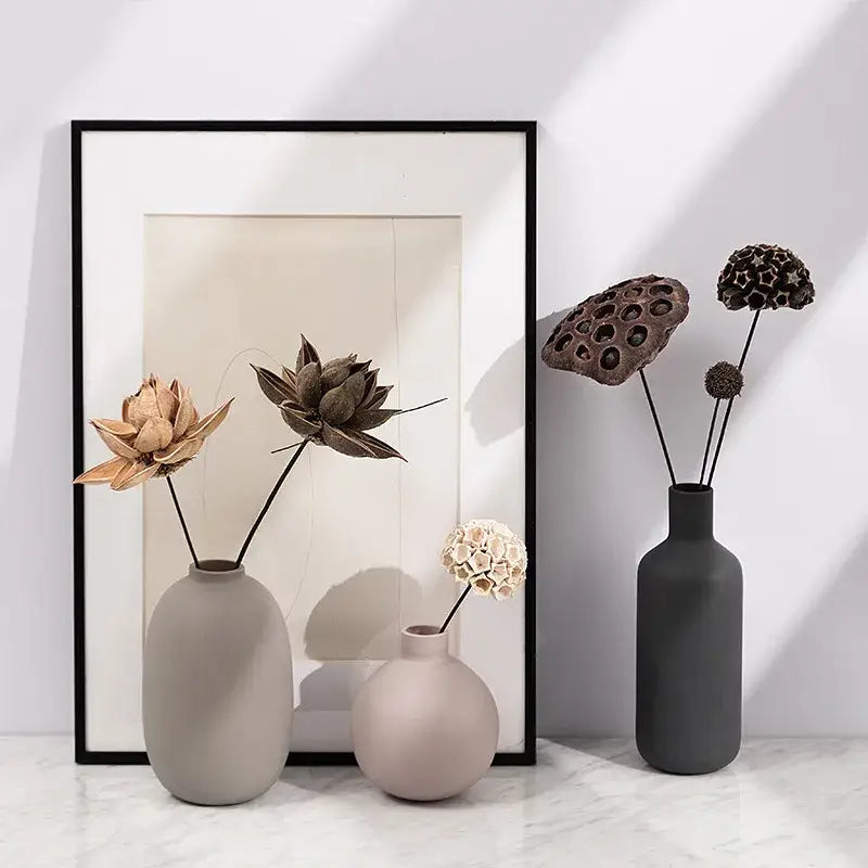 Three matte pastel geometric ceramic vases in gray beige and charcoal with dried lotus pods for decorbites geometric ceramic decor