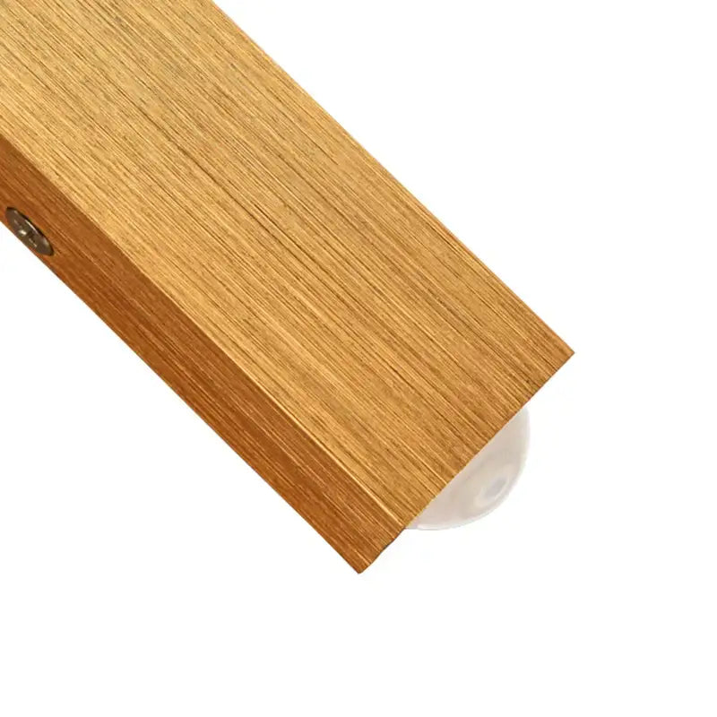 Minimalist natural wood angled wall lamp with light brown wooden door threshold and clear plastic protective cap decorbites brushed gold