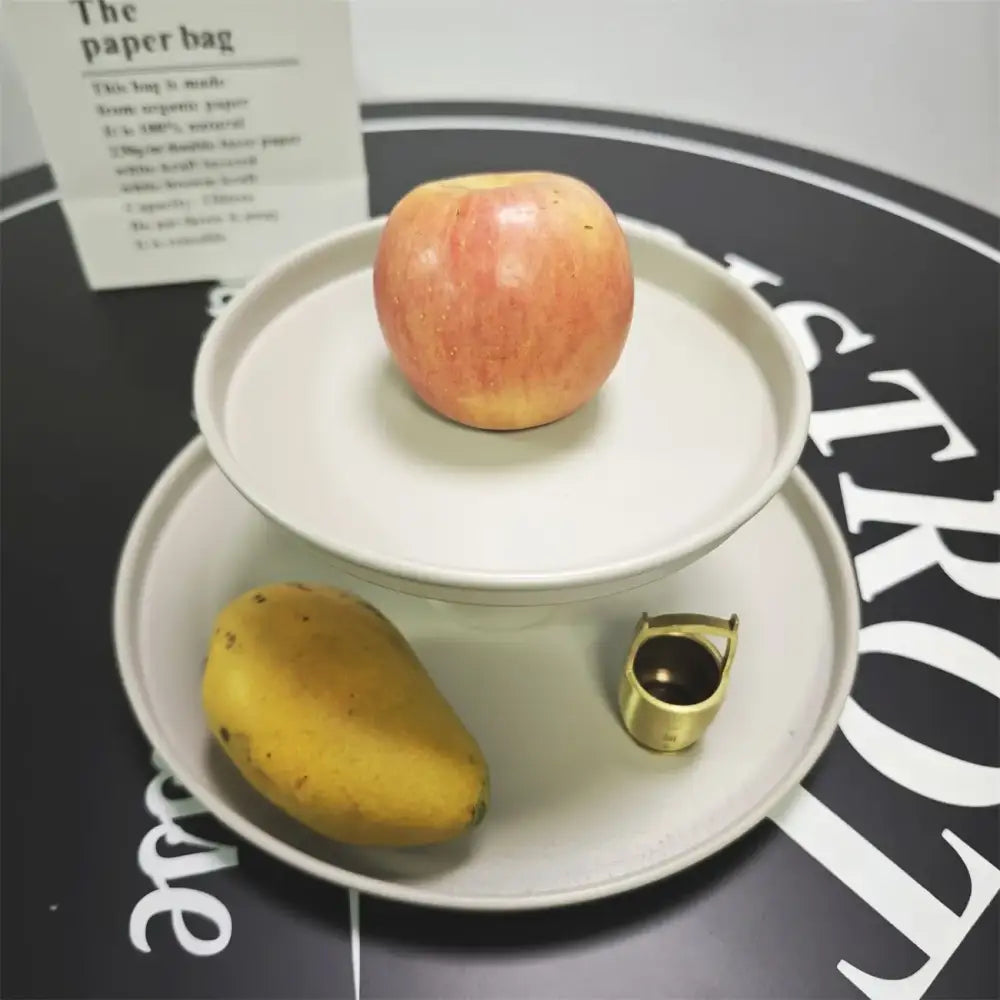 A minimalist off white ceramic birdhouse storage solution with a ripe apple on a white tiered plate by decorbites creative paper