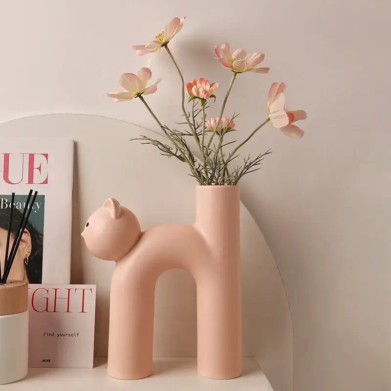 Pastel pink ceramic decorbites cathead tube vase shaped like a stylized cat with an arched back for living room decor