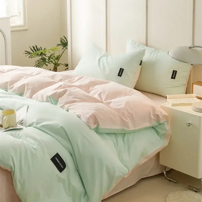 Pastel pink and mint green two-tone quilted duvet set with black brand tags in a color matching cotton bedding set