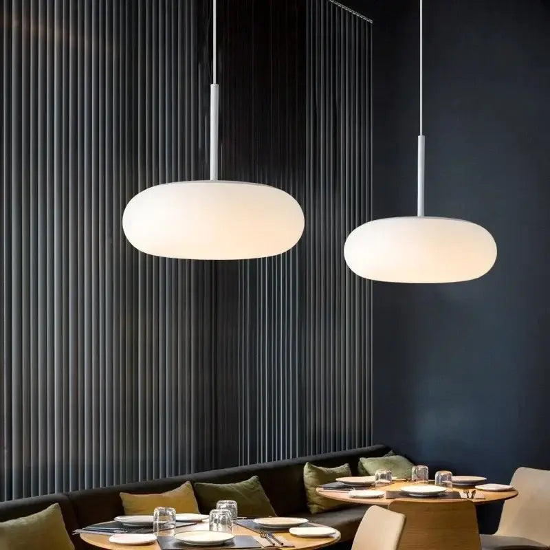 Two modern minimalist big ball pendant lamps with white frosted glass shades and slender metallic rods for living room decorbites
