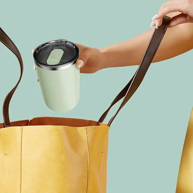 A sleek matte mint green electric magnetic stirring coffee cup with black lid and silver rim for kitchen use
