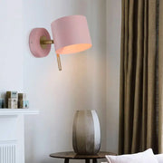 Minimalist pink cylindrical wall sconce with matte finish and brass accents for corridor lighting featuring pink yellow tones