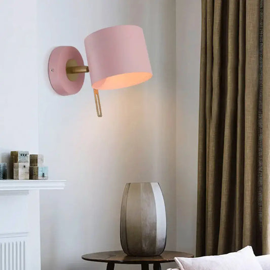 Minimalist pink cylindrical wall sconce with matte finish and brass accents for corridor lighting featuring pink yellow tones