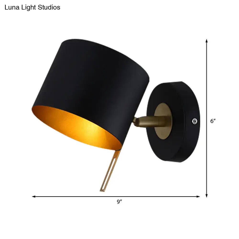 Minimalist black cylindrical wall sconce with gold interior and brass accents for corridor lighting with pink yellow tones