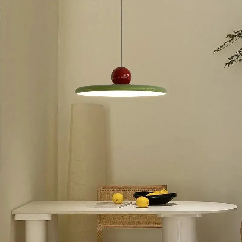 A minimalist pendant light with a glossy red spherical top and flat green cream iron art shade for bedroom decorbites