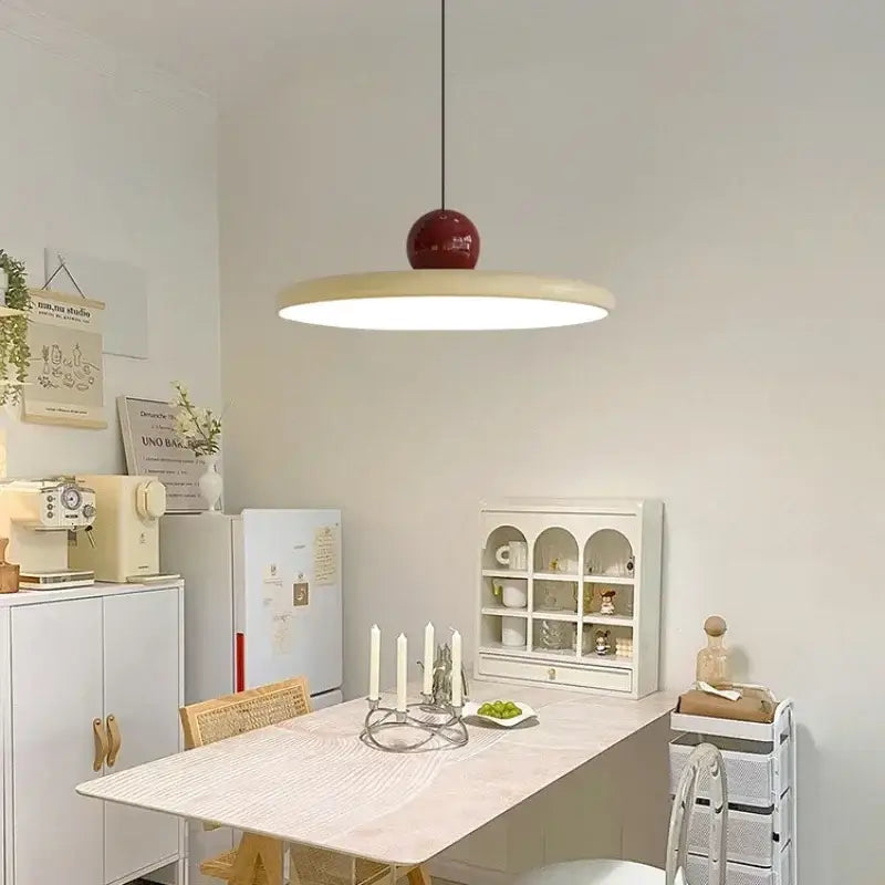 Minimalist red and white acrylic pendant light with a glossy red spherical top and cream shade for dining room cord pendant