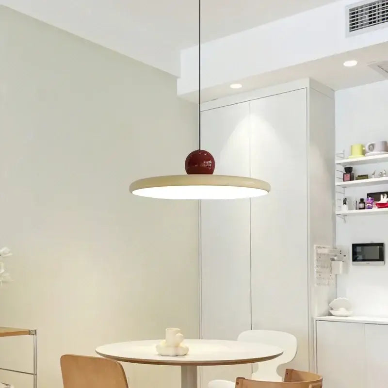 Minimalist red and white acrylic pendant light with a wooden disc and glossy red cord pendant for dining room use