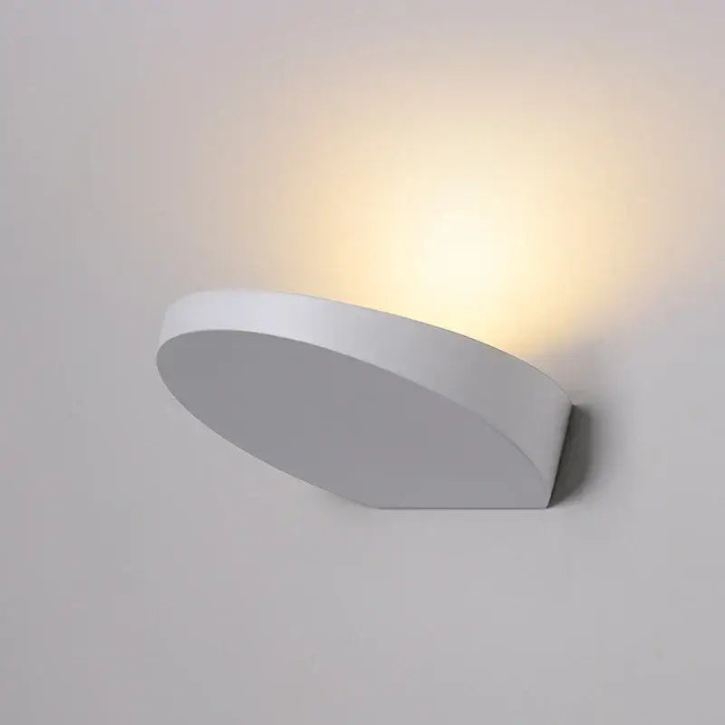 Minimalist silver and black led wall lamp with a modern white curved wall sconce emitting warm ambient light