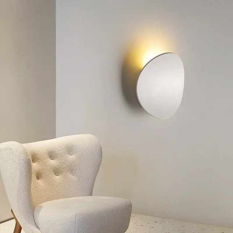 Minimalist silver and black led wall lamp with circular design and warm glow for bedroom lighting