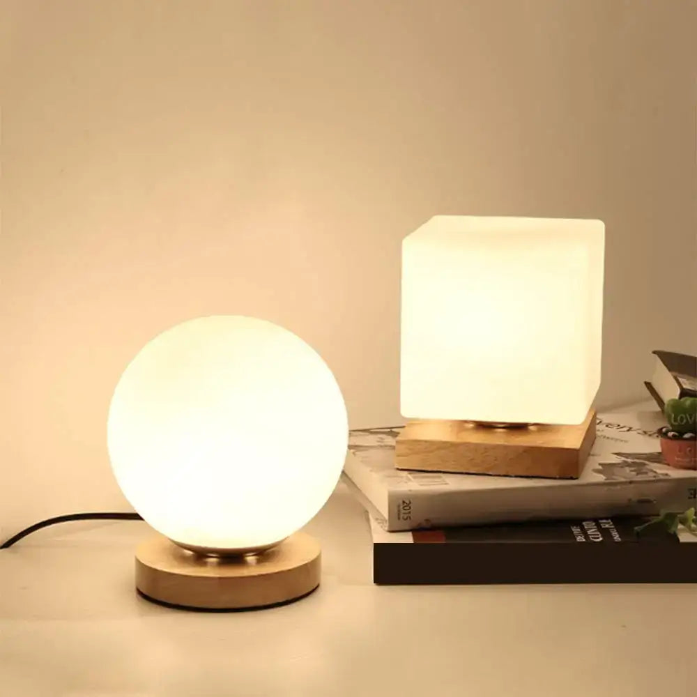 Minimalist sphere and cube decorbites glass ball table lamps with frosted glass shades and wooden bases emitting soft white glow