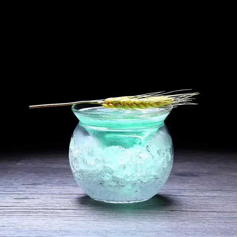 A translucent turquoise 150ml stemless martini chiller glass filled with ice and garnished with a wheat stalk for entertaining