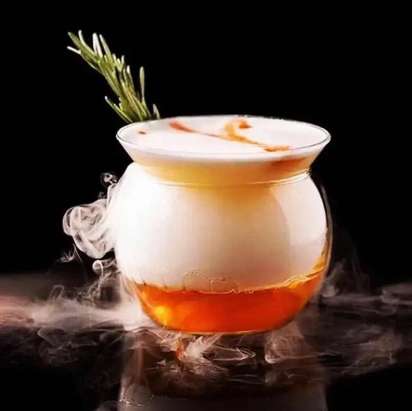 A clear glass 150ml stemless martini chiller with layered amber drink and rosemary for dining room entertaining