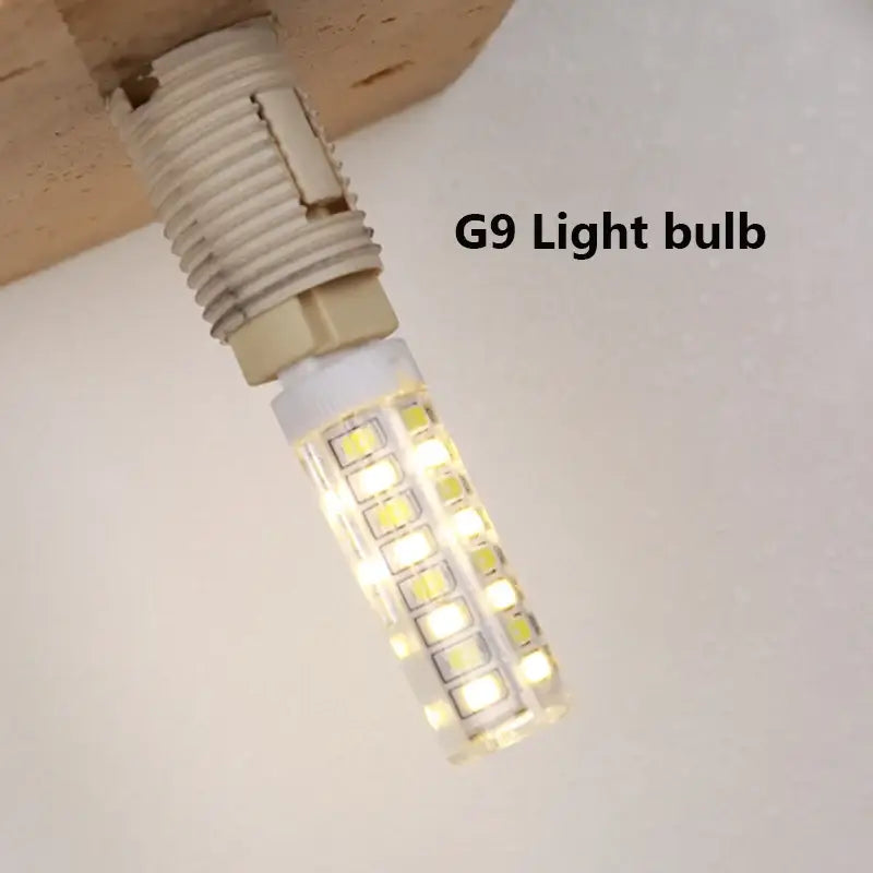 A warm white g9 led light bulb with cylindrical design in minimalist stone and decorbites glass lampshade wall light