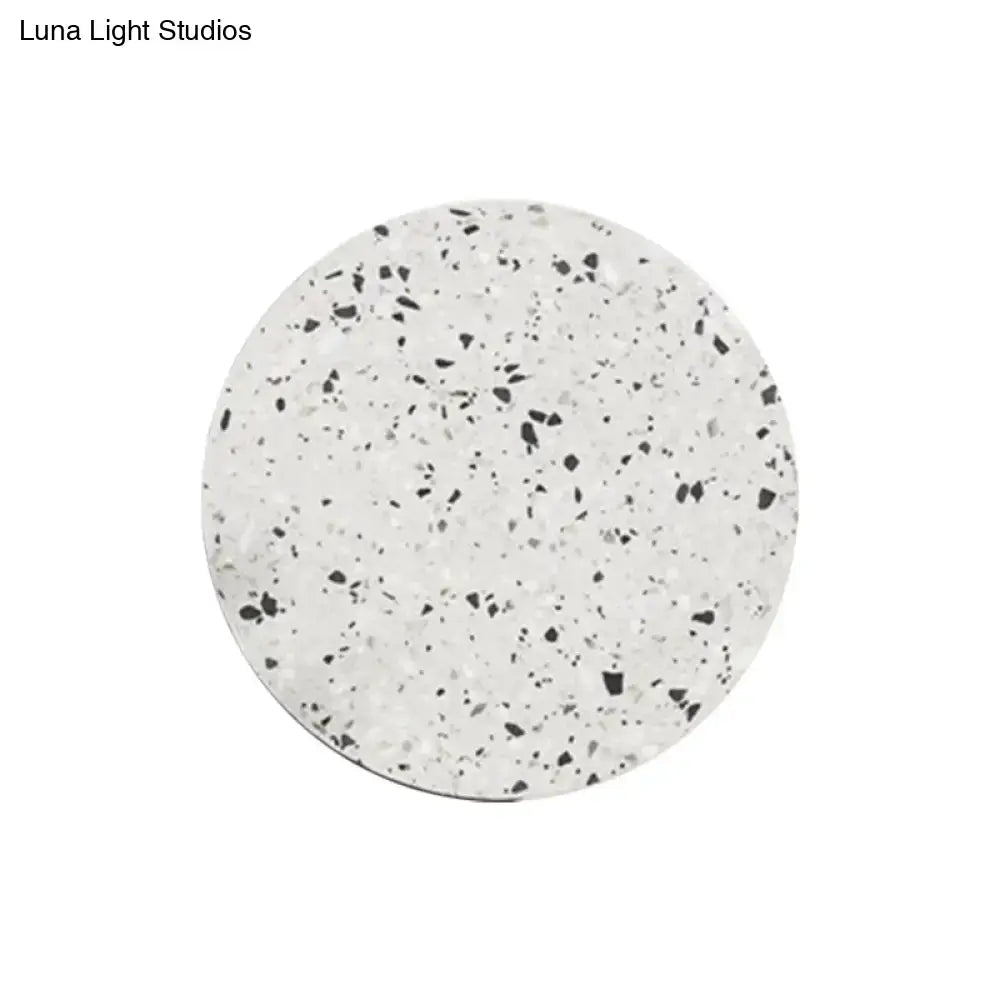 Minimalist terrazzo round LED wall sconce featuring a circular white coaster with a black and gray speckled pattern