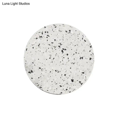 Minimalist terrazzo round LED wall sconce featuring a circular white coaster with a black and gray speckled pattern