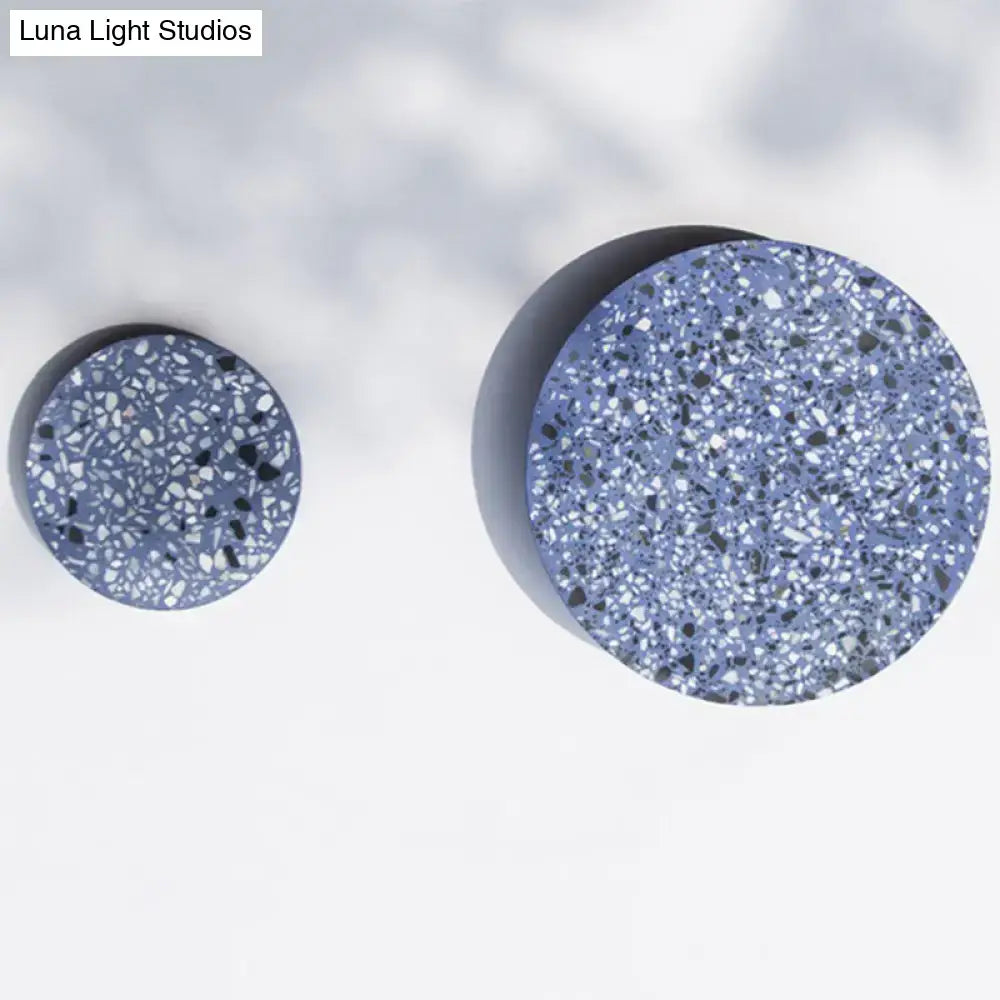 Minimalist terrazzo round led wall sconce with two circular blue and white speckled terrazzo coasters featuring black fragments