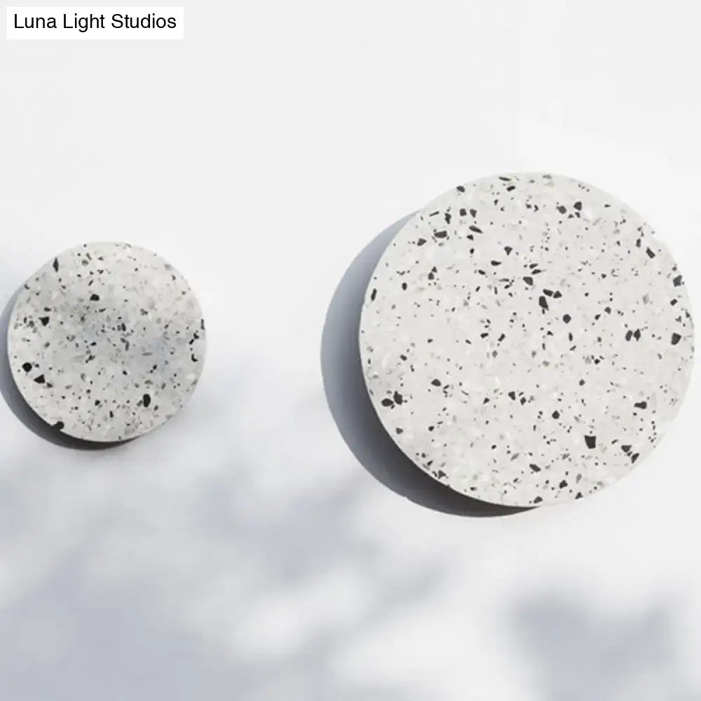 Minimalist terrazzo round led wall sconce featuring two white terrazzo coasters with black speckles for bedroom lighting