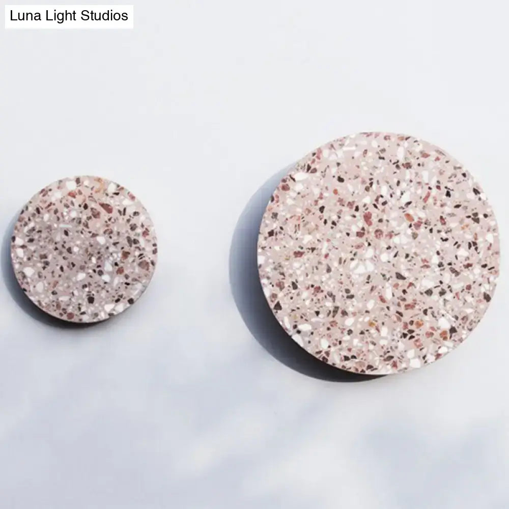 Two circular terrazzo coasters with pink white and dark flecks on a light base for minimalist bedroom lighting decor