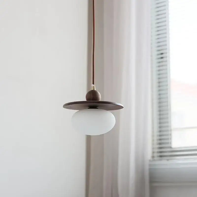 Minimalist walnut and brass glass led pendant lamp with matte white globe dark wood disc shade and copper cord for dining room