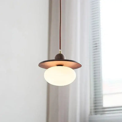 Minimalist walnut and brass glass led pendant lamp with warm brass shade and white globe bulb suspended by dark cord