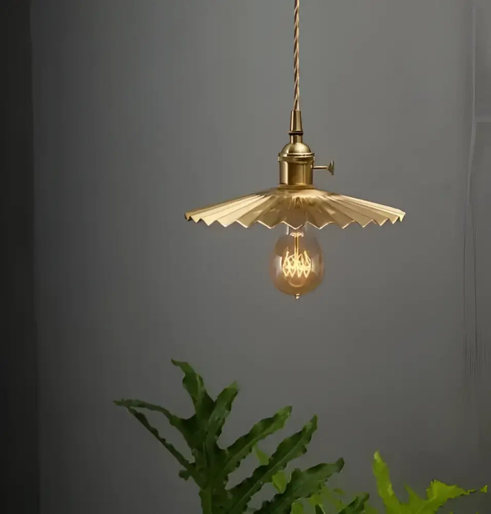 Minimalist white and black glass pendant light with brass scalloped fan-shaped shade and exposed filament bulb for bedroom