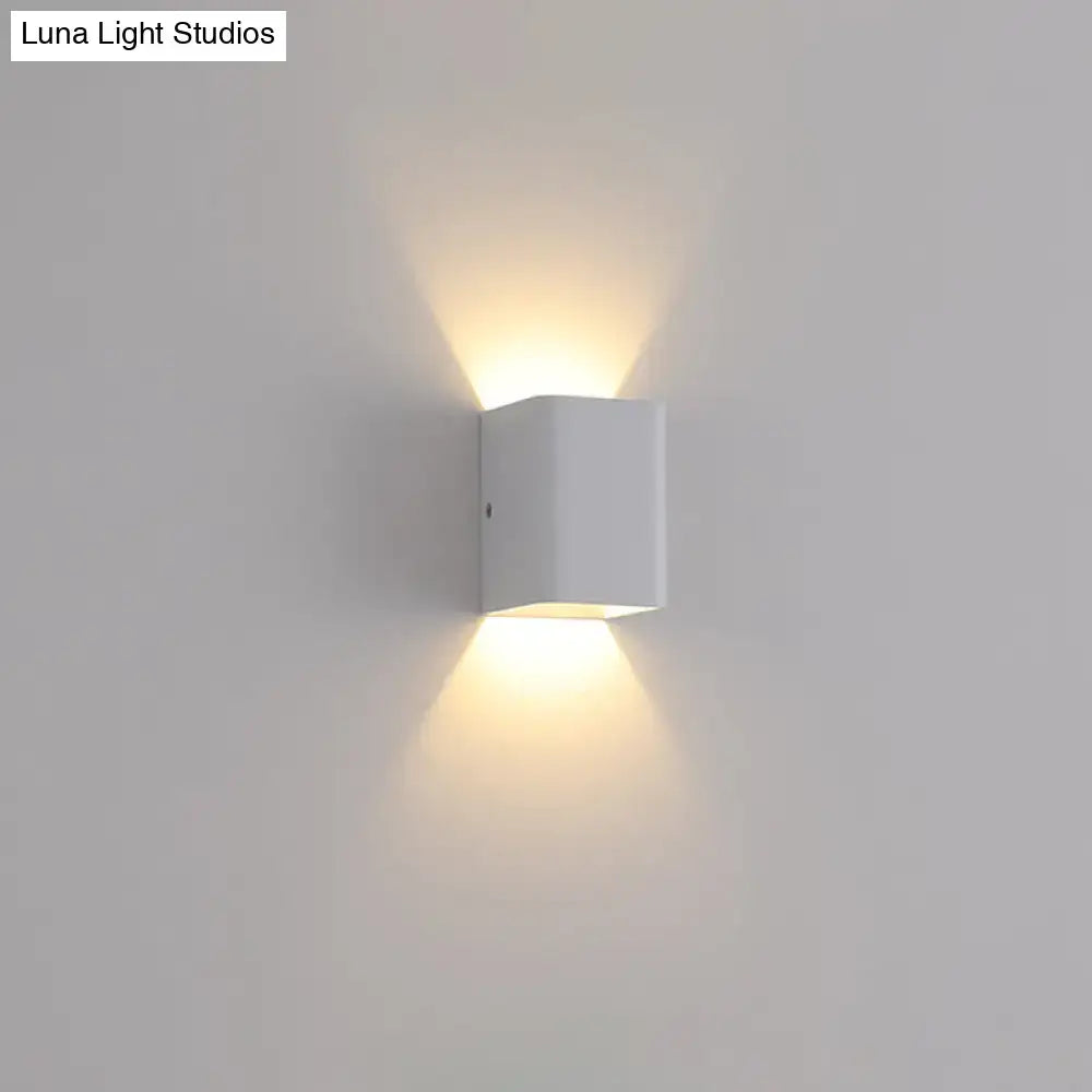 Minimalist white and brass wall lamp with cube shade emitting warm ambient light for bedroom lighting