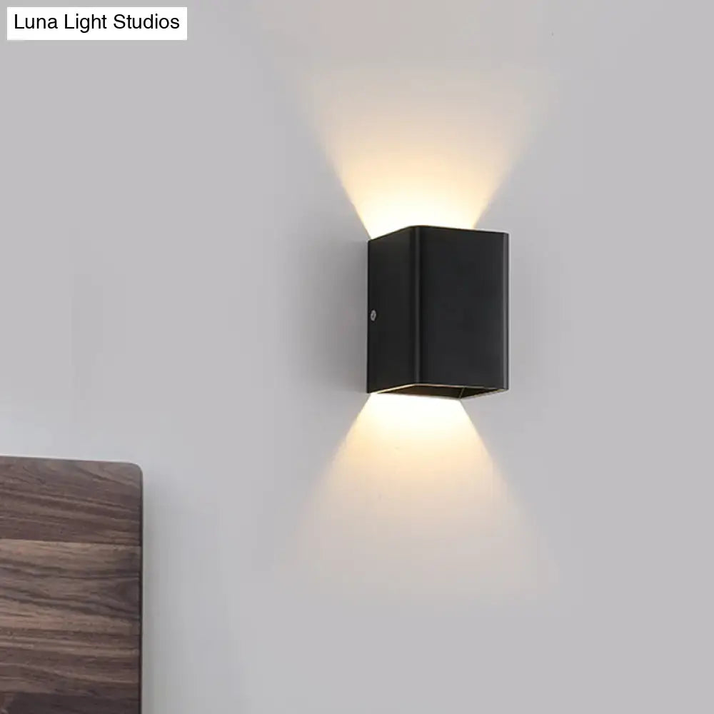 Black rectangular wall lamp with cube shade and minimalist design emitting warm light for modern bedrooms