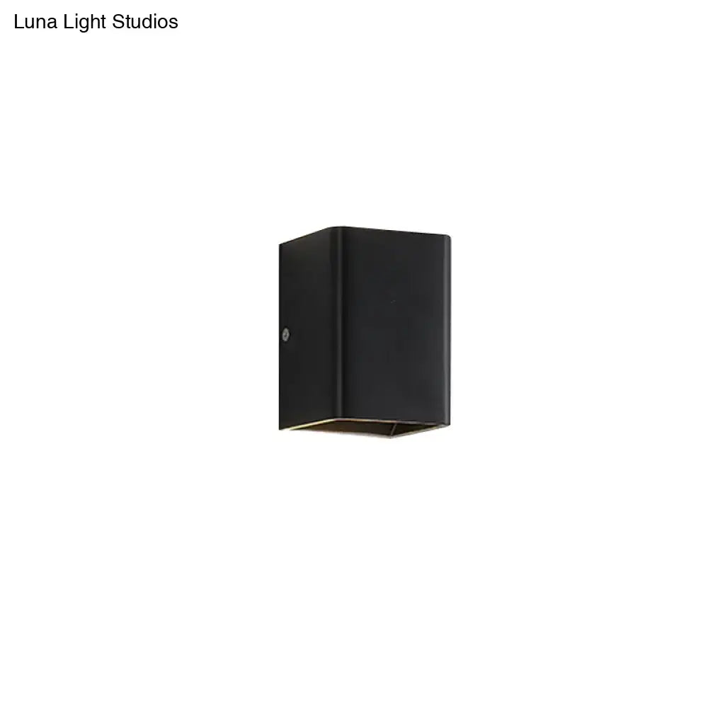 Black rectangular wall lamp with minimalist cube shade featuring sleek white and brass trim for modern bedroom lighting