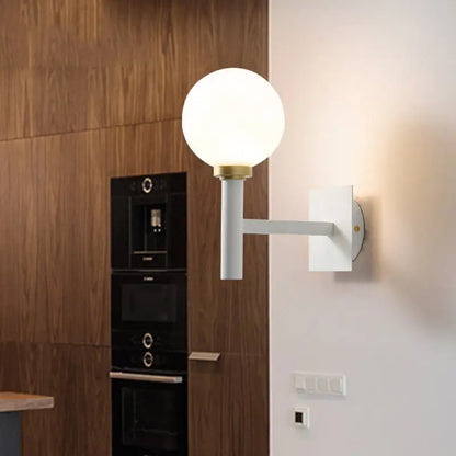 Minimalist white and brass wall lamp with spherical opal glass shade and brass accents for bedroom lighting