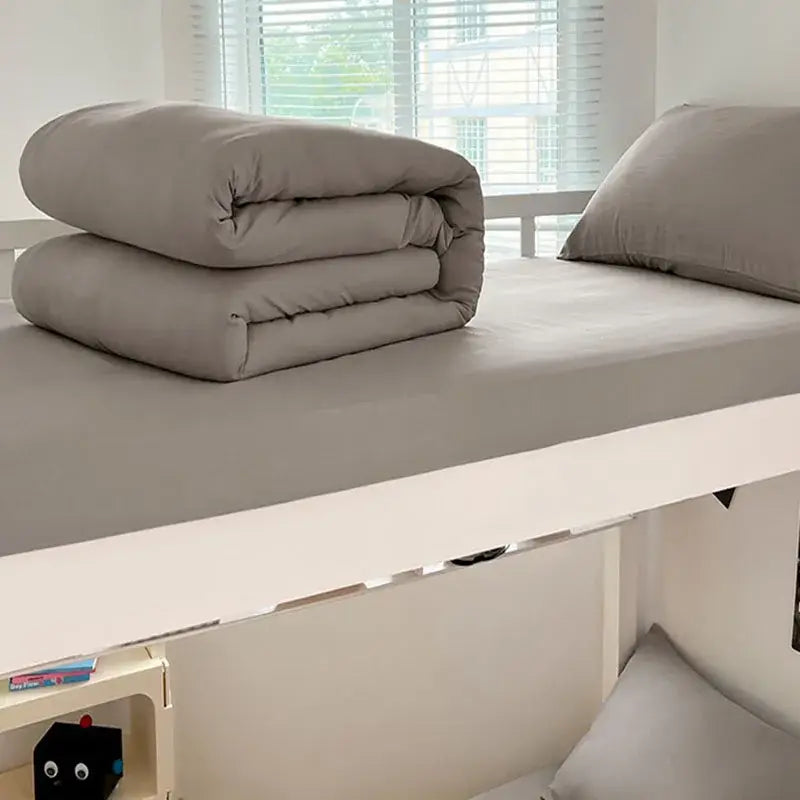 Neatly folded gray duvet cover set made of buttoned washed cotton bedding set by decorbites resting on a bed