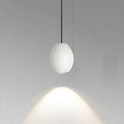 A minimalist white ceramic egg pendant light with matte finish and thin black cord decorbites adjustable pendant light